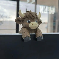 Highland cow monitor buddy on a desk setup